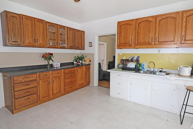 kitchen featuring brown cabinets, a sink, and glass insert cabinets