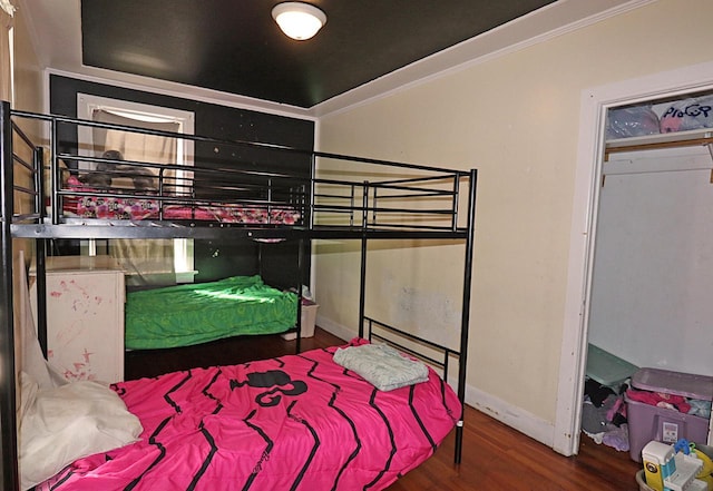 bedroom with wood finished floors, baseboards, and ornamental molding