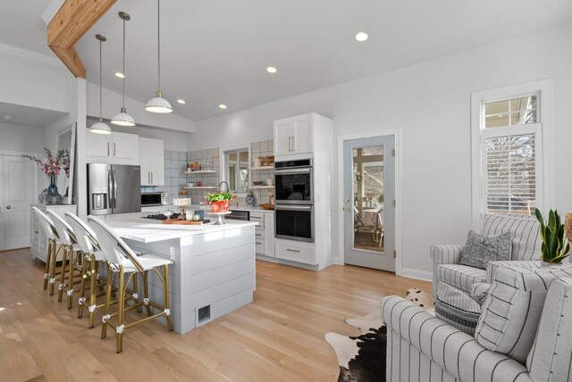 1066 Edinborough Ct, Lake Geneva, WI 53147 - kitchen featuring light countertops, open shelves, a breakfast bar area, decorative backsplash, and appliances with stainless steel finishes