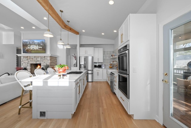 1066 Edinborough Ct, Lake Geneva, WI 53147 - kitchen with a kitchen breakfast bar, a fireplace, light countertops, lofted ceiling, and stainless steel appliances