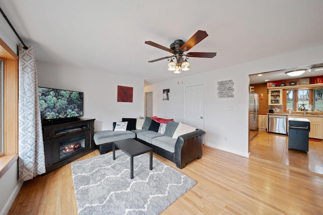 30847 Sun Ct, Burlington, WI 53105 - living area featuring a glass covered fireplace, ceiling fan, baseboards, and light wood-style floors