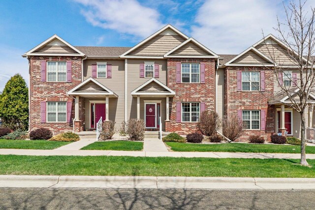 multi unit property with brick siding and a front yard