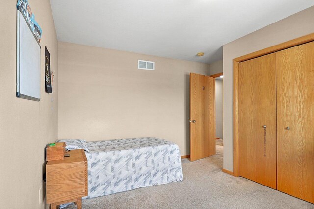 carpeted bedroom with visible vents, baseboards, and a closet