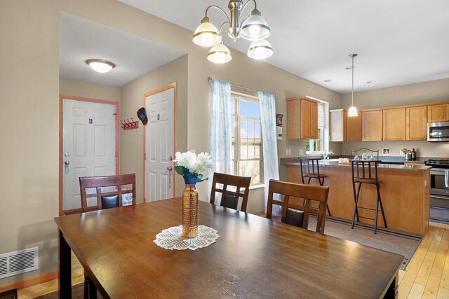 dining room featuring an inviting chandelier, light wood-type flooring, and visible vents