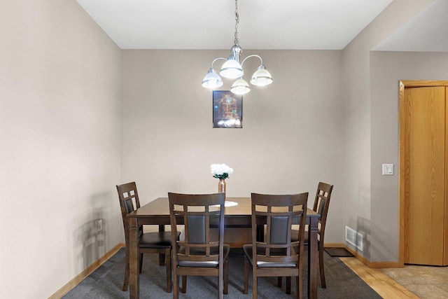 dining room with baseboards, a chandelier, wood finished floors, and visible vents