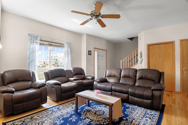 living area featuring a ceiling fan, stairs, and light wood-style flooring