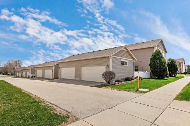 view of side of property with fence, a yard, and community garages