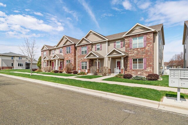 townhome / multi-family property with a residential view, a front lawn, and brick siding