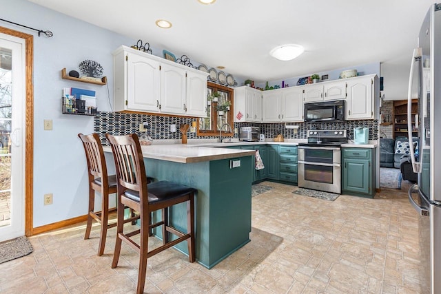 101 Brookview Pl, Combined Locks, WI 54113 - kitchen with appliances with stainless steel finishes, a peninsula, tasteful backsplash, white cabinetry, and a breakfast bar area