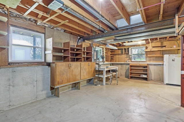 basement featuring a workshop area and freestanding refrigerator
