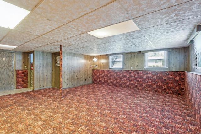 basement featuring wooden walls and a drop ceiling