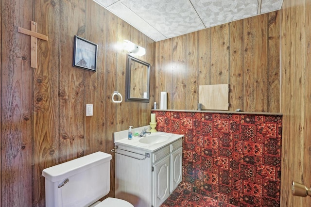 half bath with wood walls, toilet, and vanity