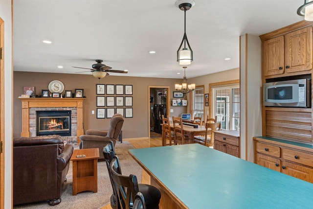 interior space with recessed lighting, a fireplace, baseboards, and ceiling fan with notable chandelier