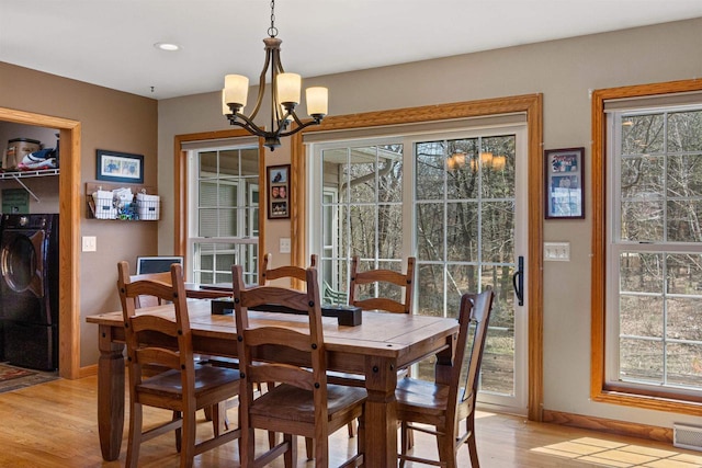 dining room featuring separate washer and dryer, plenty of natural light, a notable chandelier, and light wood-type flooring