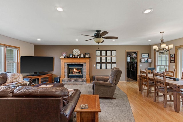 living area featuring light wood-type flooring, plenty of natural light, recessed lighting, and ceiling fan with notable chandelier