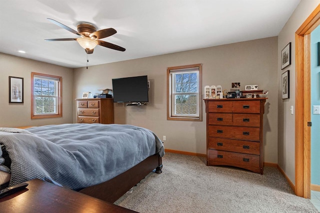 bedroom featuring light colored carpet, baseboards, a ceiling fan, and multiple windows