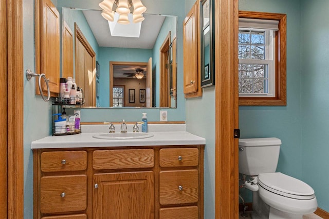 half bath featuring a skylight, a ceiling fan, vanity, and toilet