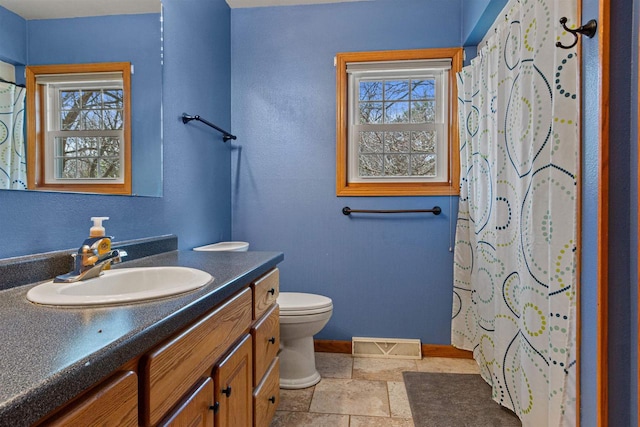 bathroom with a wealth of natural light, toilet, vanity, and visible vents