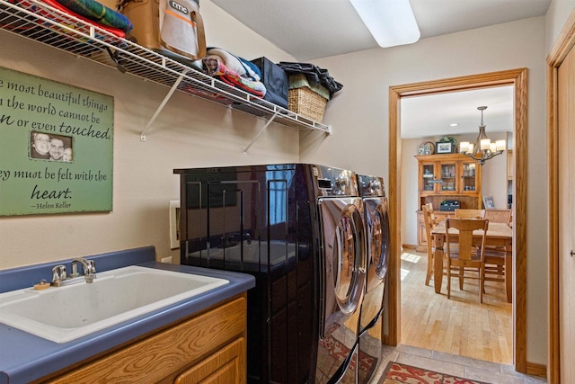laundry area with washing machine and dryer, an inviting chandelier, a sink, and laundry area