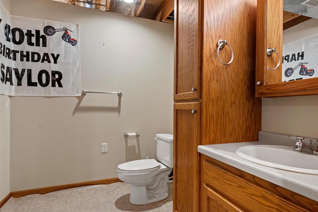 half bathroom featuring baseboards, toilet, and vanity