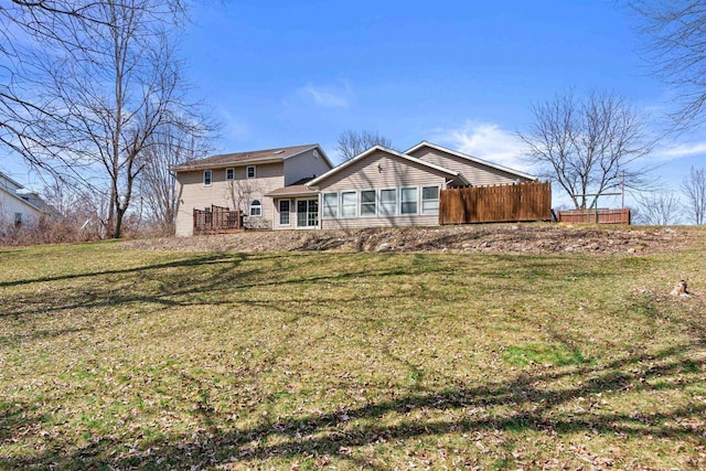 rear view of property with a lawn and fence