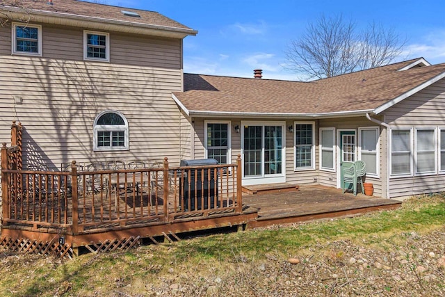 rear view of property featuring roof with shingles and a deck