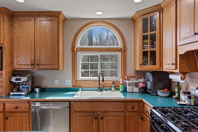 kitchen with stainless steel dishwasher, range with gas stovetop, a sink, glass insert cabinets, and light countertops