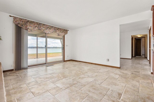 2151 Sunrise Dr, Appleton, WI 54914 - empty room with stone tile floors, baseboards, visible vents, and a water view