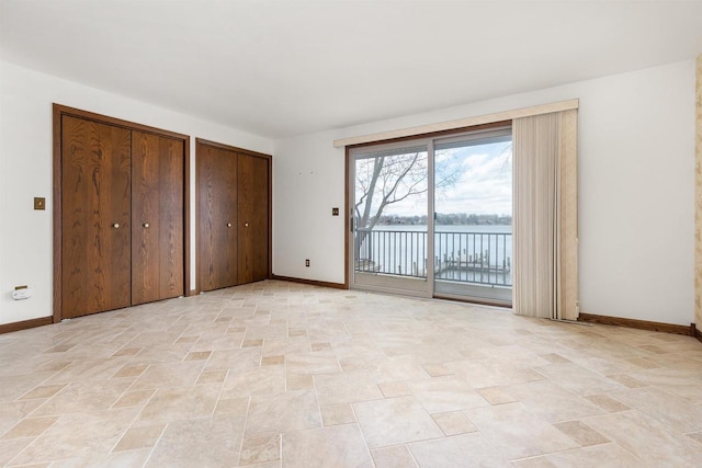 2151 Sunrise Dr, Appleton, WI 54914 - unfurnished bedroom with stone finish floor, a water view, baseboards, two closets, and access to outside