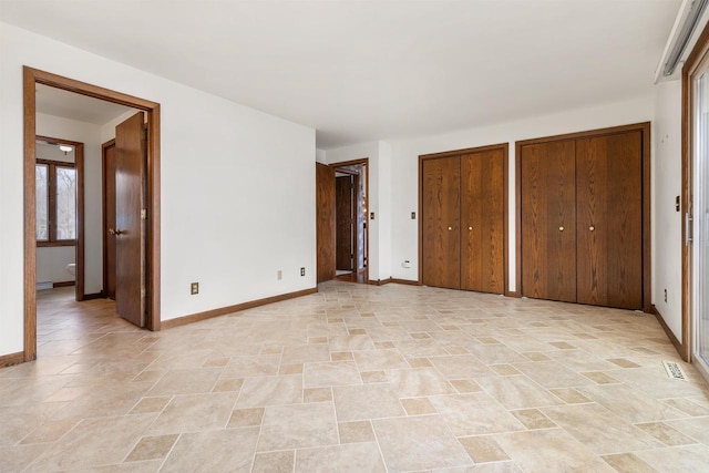 2151 Sunrise Dr, Appleton, WI 54914 - unfurnished bedroom with ensuite bath, baseboards, multiple closets, and stone finish floor