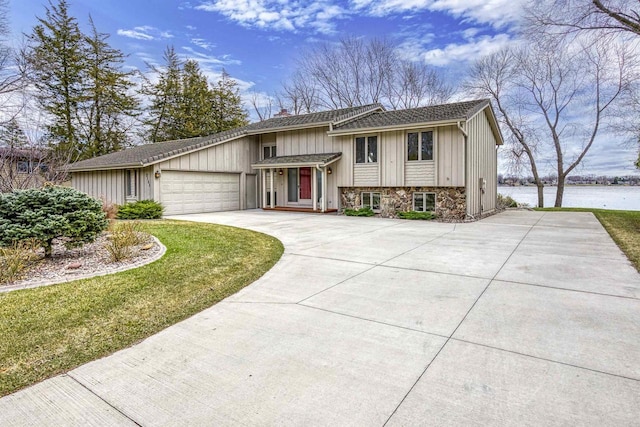 2151 Sunrise Dr, Appleton, WI 54914 - view of front of property featuring a chimney, a water view, concrete driveway, stone siding, and a garage