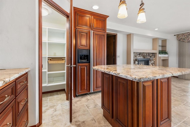 2151 Sunrise Dr, Appleton, WI 54914 - kitchen featuring built in shelves, pendant lighting, light stone counters, a kitchen island, and a fireplace