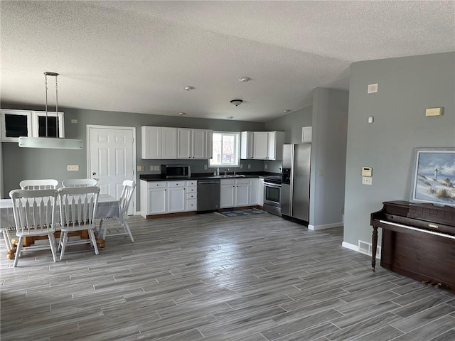 948 Wissota Green Pkwy, Chippewa Falls, WI 54729 - kitchen with dark countertops, wood finished floors, white cabinets, baseboards, and appliances with stainless steel finishes