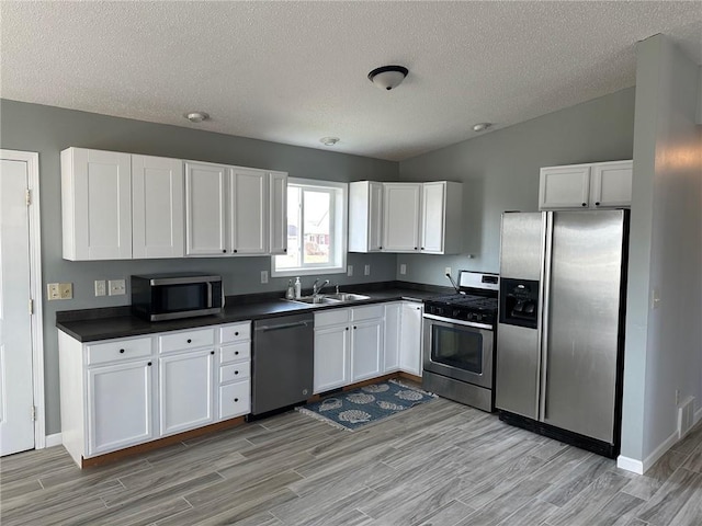 948 Wissota Green Pkwy, Chippewa Falls, WI 54729 - kitchen with dark countertops, appliances with stainless steel finishes, light wood-style floors, and white cabinets