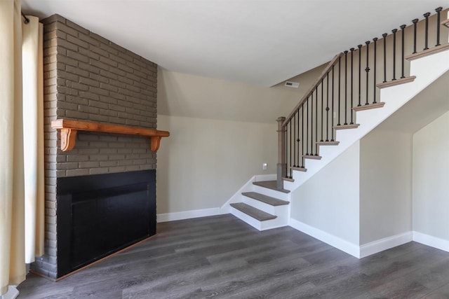 317 Darby Ct, Nekoosa, WI 54457 - unfurnished living room featuring dark wood-style floors, baseboards, visible vents, a brick fireplace, and stairs