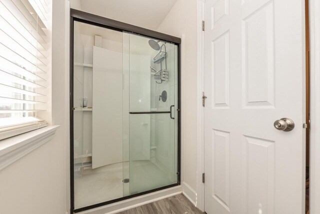 430 Ashley Dr, Williams Bay, WI 53191 - full bathroom featuring baseboards, wood finished floors, and a stall shower