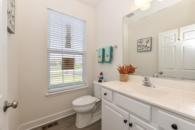 430 Ashley Dr, Williams Bay, WI 53191 - half bath featuring toilet, baseboards, visible vents, wood finished floors, and vanity