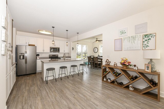 430 Ashley Dr, Williams Bay, WI 53191 - kitchen featuring white cabinets, stainless steel appliances, a ceiling fan, wood finished floors, and a breakfast bar