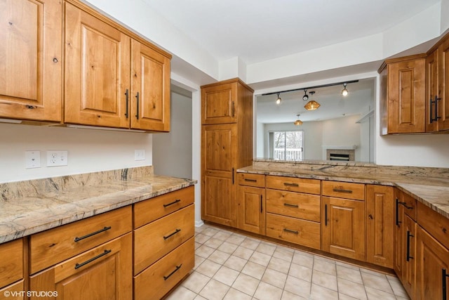 110 W St Unit 1, Lake Geneva, WI 53147 - kitchen with a fireplace, brown cabinetry, rail lighting, and light tile patterned floors