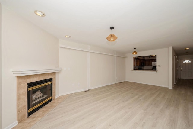 110 W St Unit 1, Lake Geneva, WI 53147 - unfurnished living room with recessed lighting, a tile fireplace, baseboards, and light wood-type flooring