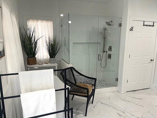 full bath with marble finish floor and a stall shower