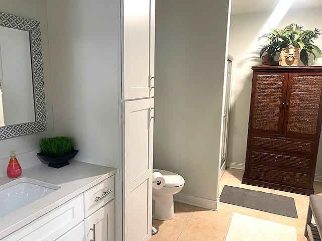 bathroom featuring a shower stall, tile patterned floors, vanity, baseboards, and toilet