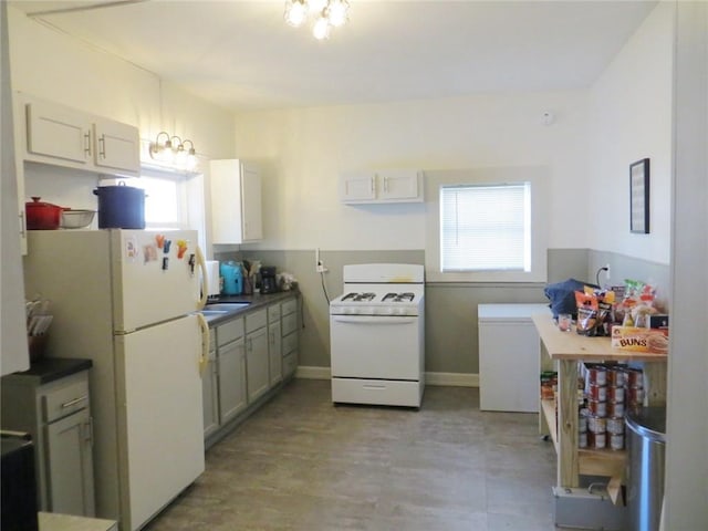 kitchen with a chandelier, dark countertops, and white appliances