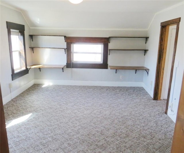 empty room featuring vaulted ceiling, baseboards, carpet, and crown molding