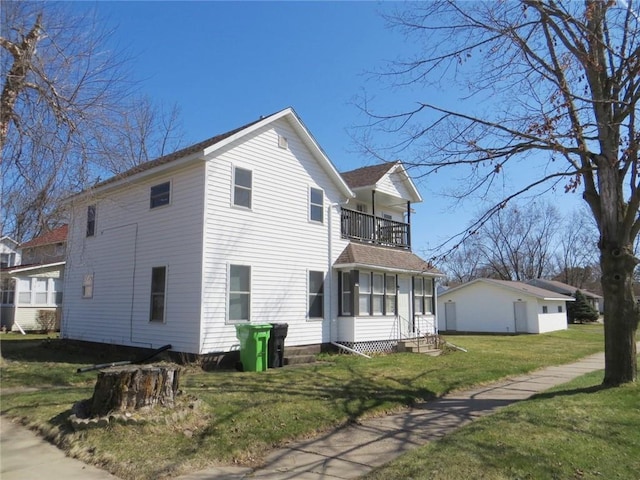 view of property exterior featuring a lawn, a balcony, and entry steps