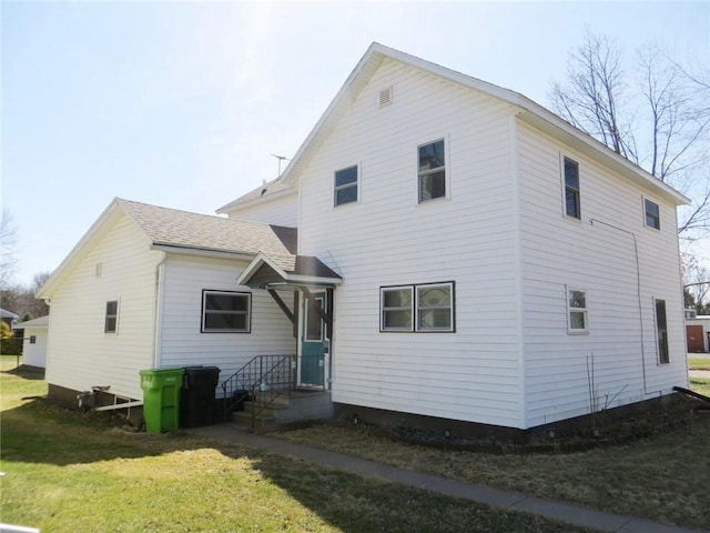 back of property featuring a lawn and a shingled roof