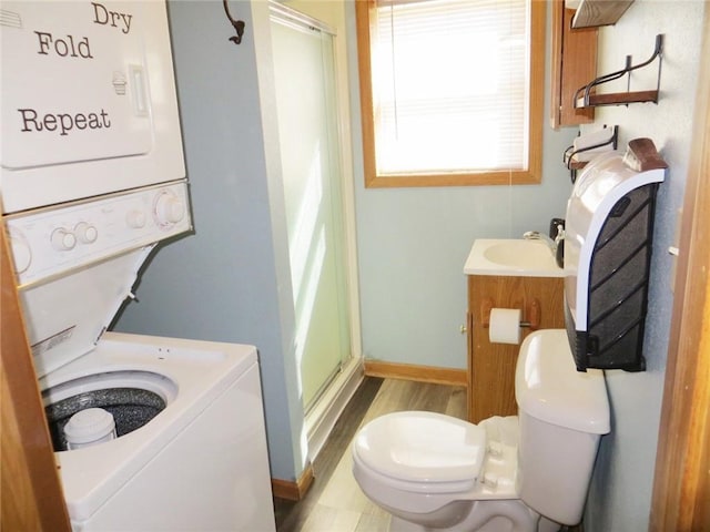 bathroom with toilet, a stall shower, vanity, stacked washer / drying machine, and baseboards