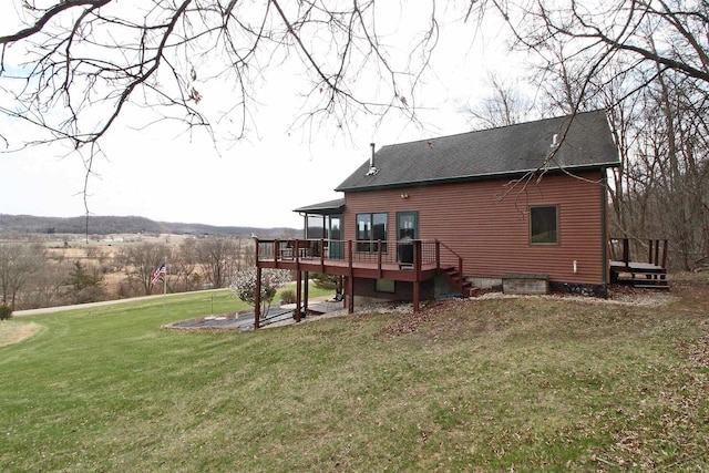 rear view of house featuring a wooden deck, a lawn, and a shingled roof