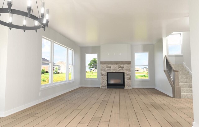 310 Kiddle Ln Unit Lt60, Union Grove, WI 53182 - unfurnished living room with stairway, light wood finished floors, an inviting chandelier, a stone fireplace, and baseboards