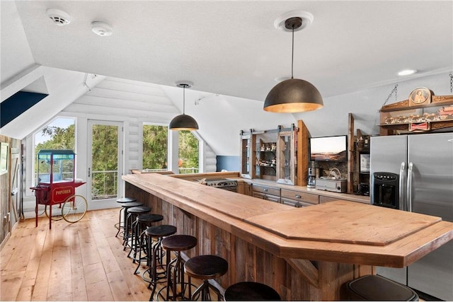 1211 172nd Ave, Balsam Lake, WI 54810 - kitchen with light wood finished floors, stainless steel fridge with ice dispenser, vaulted ceiling, a breakfast bar, and pendant lighting